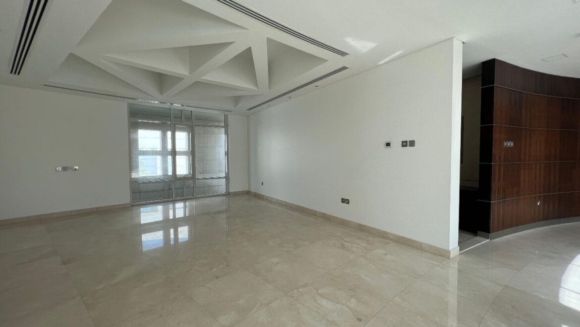 Front exterior of a modern, spacious four-bedroom independent villa in Al Heerah, Sharqan, Sharjah with a manicured lawn and driveway.-Propertyana real estate in dubai and sharjeh