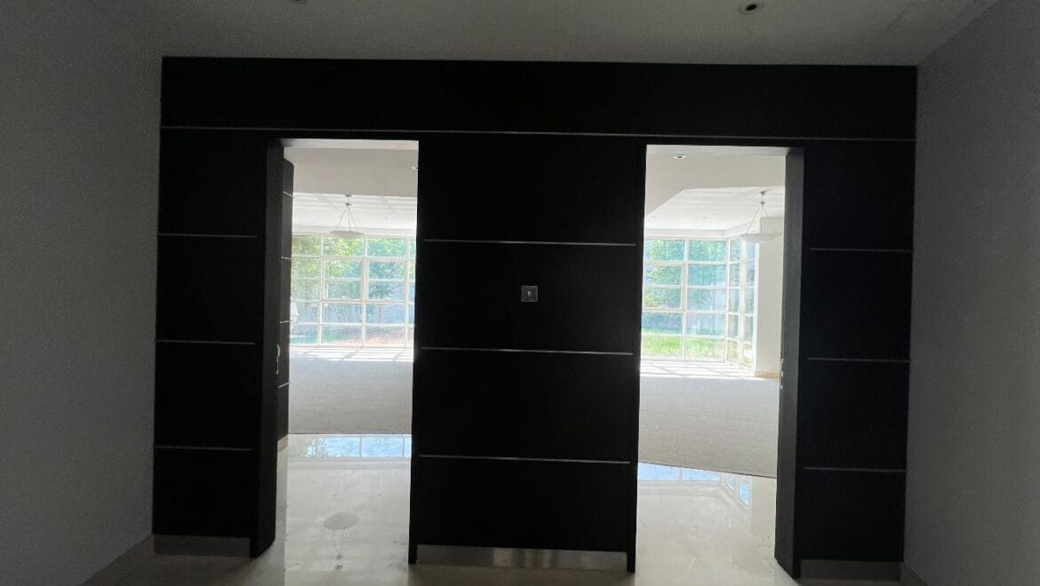 Front exterior of a modern, spacious four-bedroom independent villa in Al Heerah, Sharqan, Sharjah with a manicured lawn and driveway.-Propertyana real estate in dubai and sharjeh