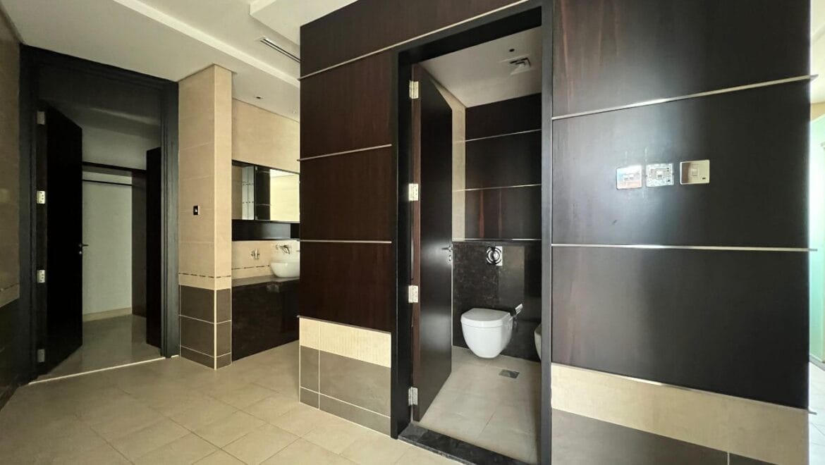 Front exterior of a modern, spacious four-bedroom independent villa in Al Heerah, Sharqan, Sharjah with a manicured lawn and driveway.-Propertyana real estate in dubai and sharjeh