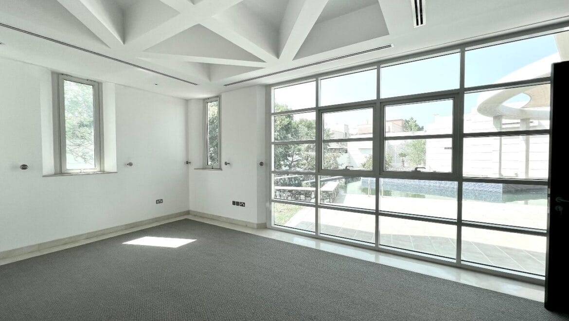 Front exterior of a modern, spacious four-bedroom independent villa in Al Heerah, Sharqan, Sharjah with a manicured lawn and driveway.-Propertyana real estate in dubai and sharjeh