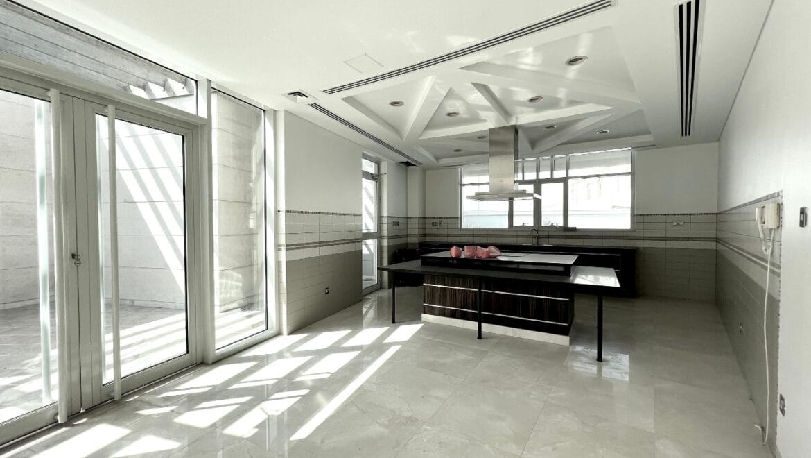 Front exterior of a modern, spacious four-bedroom independent villa in Al Heerah, Sharqan, Sharjah with a manicured lawn and driveway.-Propertyana real estate in dubai and sharjeh