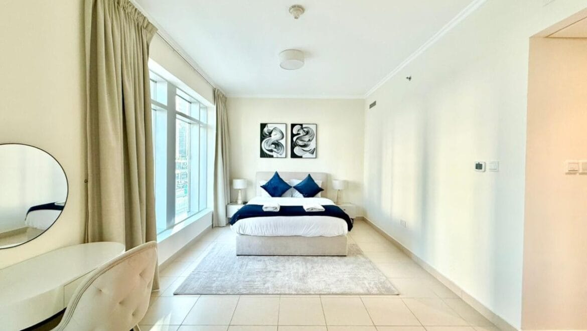 Studio bedroom interior in a residential apartment at Burj Views Podium, Downtown Dubai, featuring modern furnishings and a large window with city skyline views.-Propertyana real estate in dubai and sharjeh