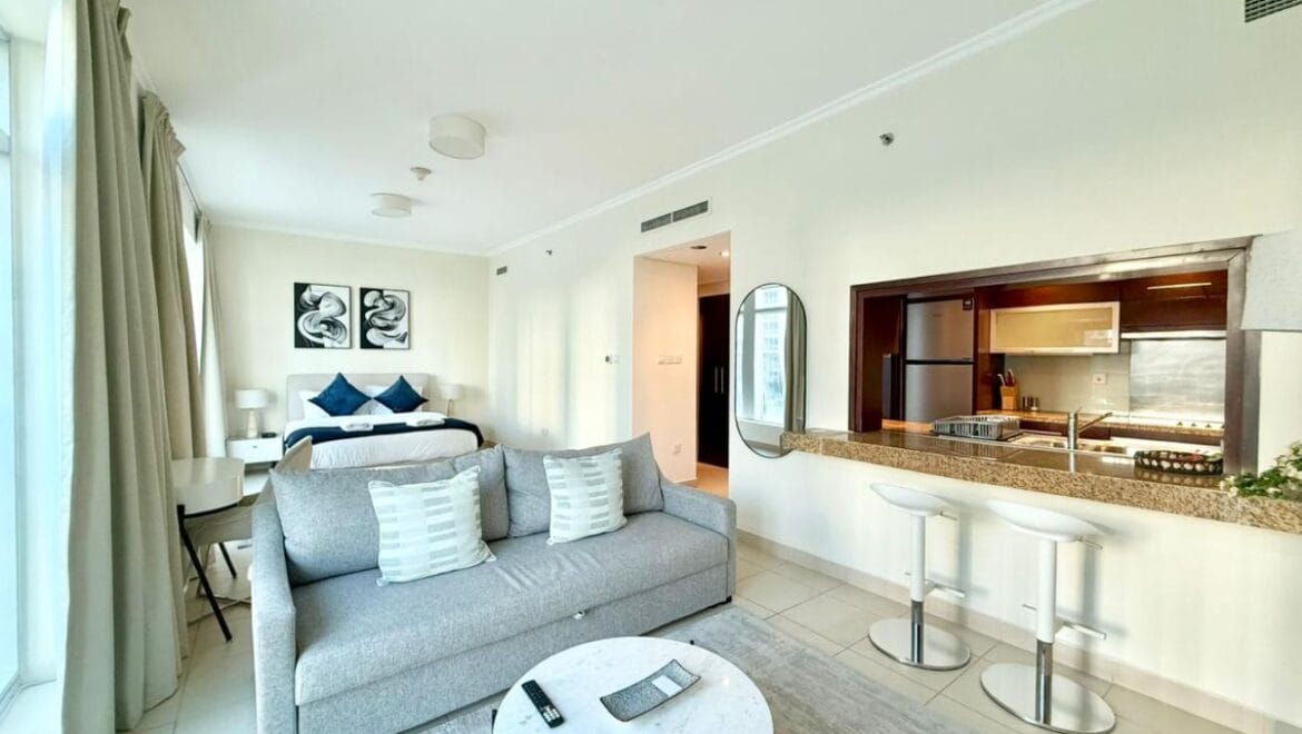 Studio bedroom interior in a residential apartment at Burj Views Podium, Downtown Dubai, featuring modern furnishings and a large window with city skyline views.-Propertyana real estate in dubai and sharjeh