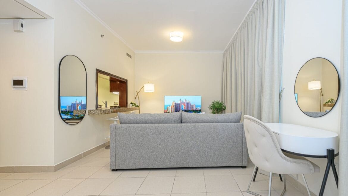 Studio bedroom interior in a residential apartment at Burj Views Podium, Downtown Dubai, featuring modern furnishings and a large window with city skyline views.-Propertyana real estate in dubai and sharjeh