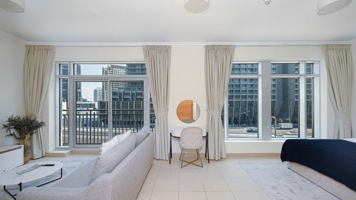 Studio bedroom interior in a residential apartment at Burj Views Podium, Downtown Dubai, featuring modern furnishings and a large window with city skyline views.-Propertyana real estate in dubai and sharjeh
